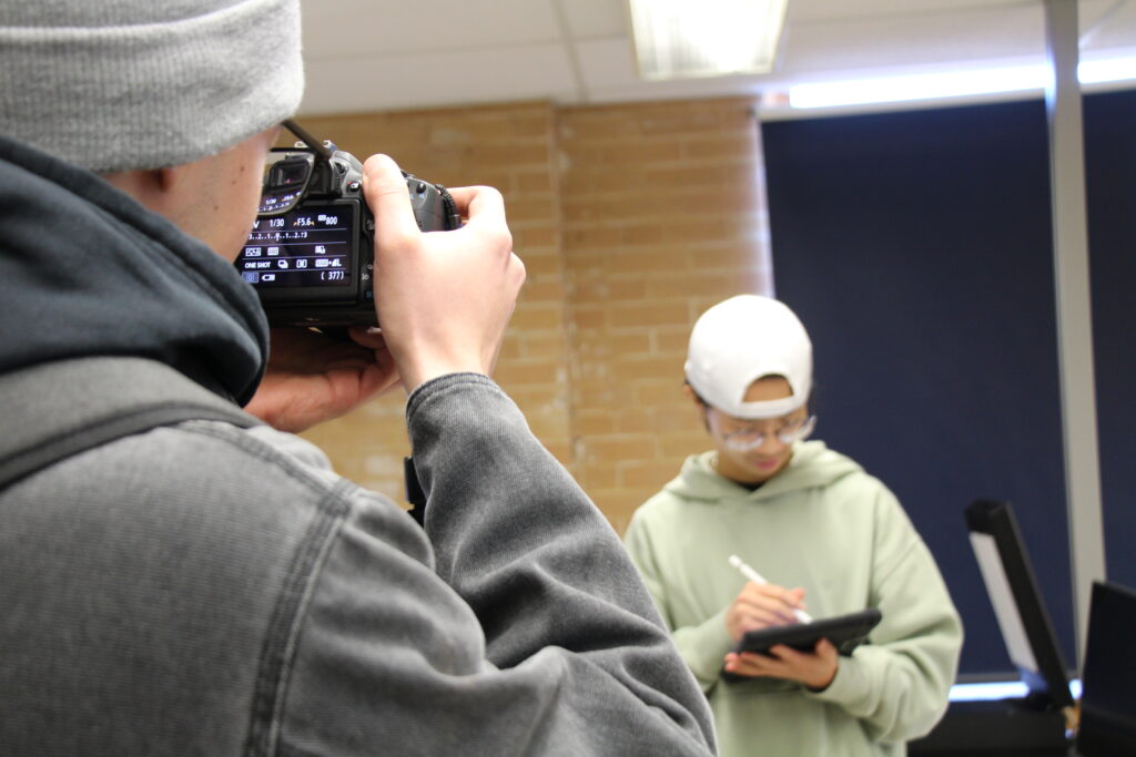 Image of person taking a picture of a person drawing on an iPad